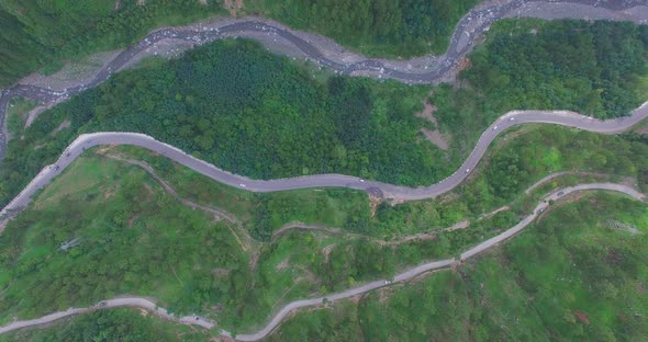 Zigzag road top view, Kahmir, India, Traffice is going on, Big forest and green trees, tow zigzag ro