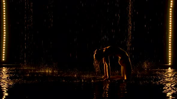 Silhouette of Attractive Woman Performing Bridge Pose. The Yellow Light Falls Softly on the Wet Body