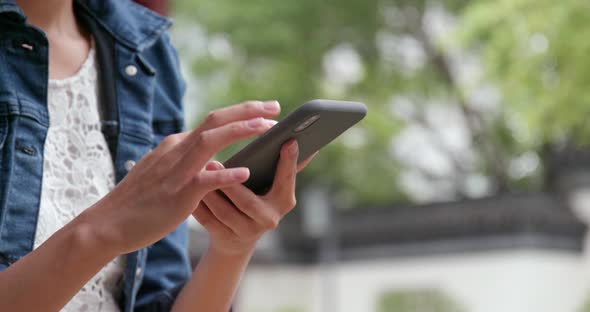 Woman use of mobile phone in Chinese garden