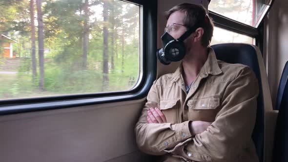 a Man in a Respirator Goes to Work on the Train Sitting in Front of a Window