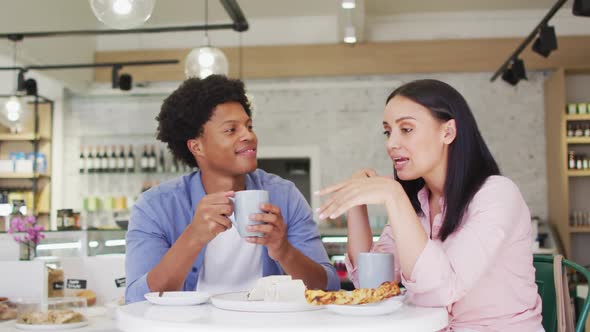 Video of happy diverse woman and man drinking and talking at coffee shop