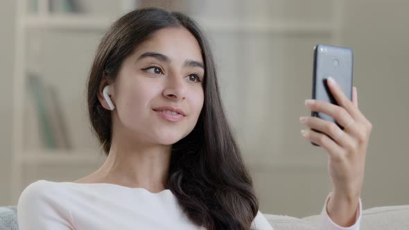 Arabian Young Blogger Woman Wears Earphones Waving Hand Saying Hello at Mobile Camera Streaming