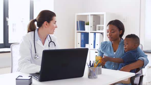 Mother with Baby and Doctor with Laptop at Clinic