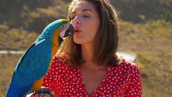 Pretty Model Blows a Kiss to Her Pet Macaw Parrot on a Sunny Day