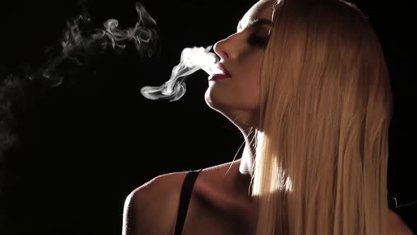 Girl Smokes an Electronic Cigarette in an Empty Room. Black Background