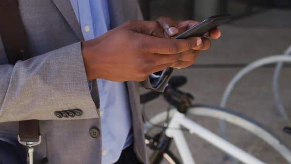 African american businessman using smartphone outside of modern office building