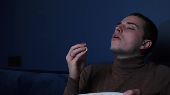 Portrait Joyful Caucasian Man Sitting on Sofa at Home Throwing Popcorn and Catching It with His