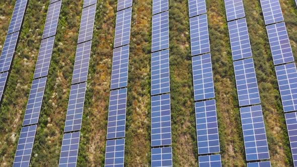 Aerial flying over group of solar panels in  farm field - Italy