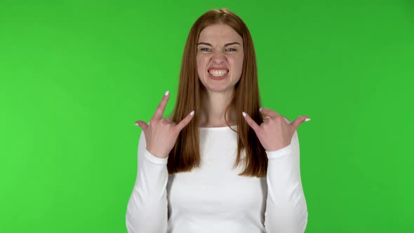 Portrait of Pretty Young Woman Is Making a Rock Gesture and Enjoying Life