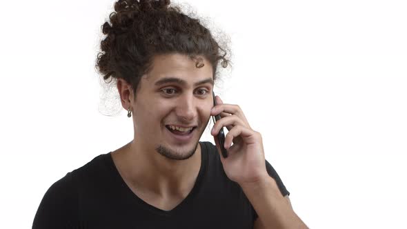 Closeup of Handsome Young Man with Ponytail Hairstyle and Beard Talking on Mobile Phone and Agree