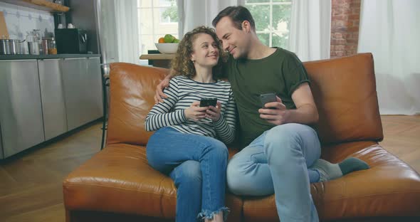 Young Man and Woman Talking with Phones in Hands