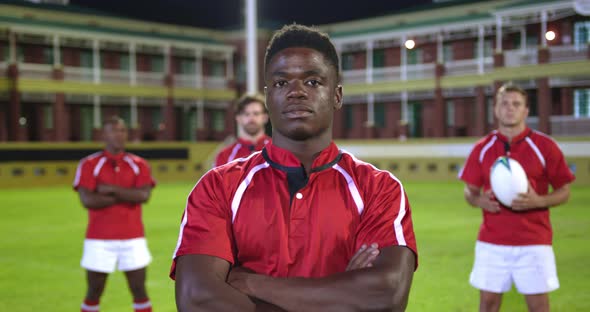 Male rugby players with rugby ball and arms crossed standing in stadium 4k