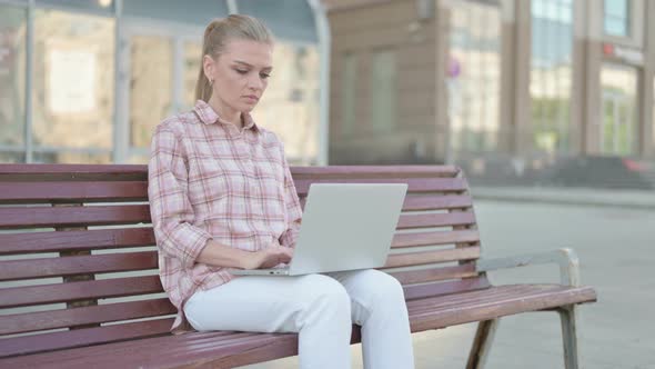 Rejecting Young Woman in Denial While Using Laptop Sitting Outdoor on Bench