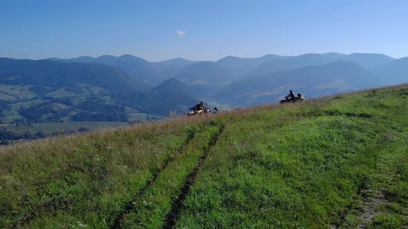 ATV Riders on Grassy Mountain Hill on a Sunny Day in Summer