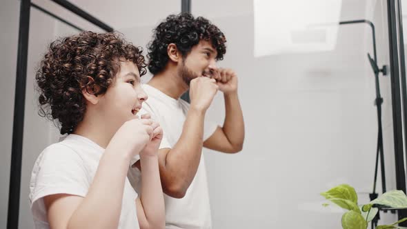 Curlyhaired Brothers Take Care of Oral Hygiene in Bathroom
