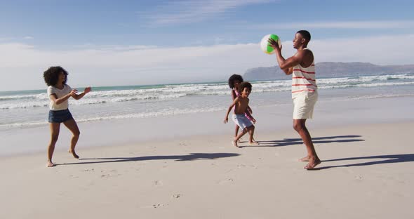 African american parents and their children playing with a ball on the beach
