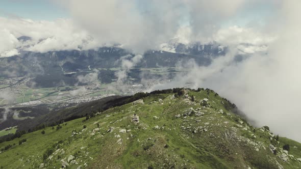 Aerial drone shot of a grass covered mountain top, Lagoz with a small trail leading up with clouds a