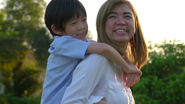 Asian Child On A Piggy Back Ride With His Mother Outdoor