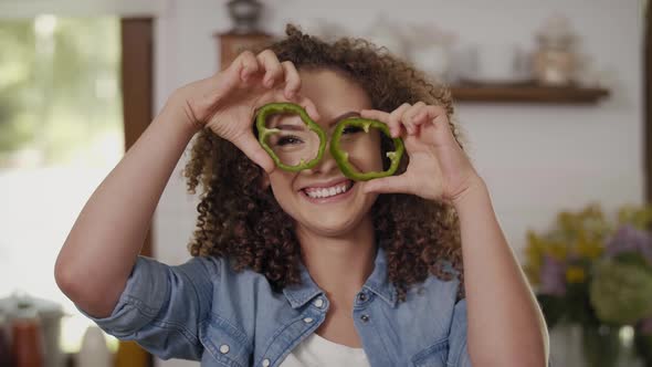 Young woman having fun with pepper in the kitchen