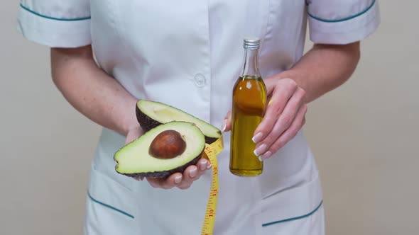 Nutritionist Doctor Holding Organic Avocado Fruit and Bottle of Oil