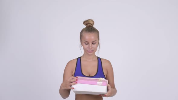 Happy Young Blonde Woman Looking Surprised While Opening Gift Box