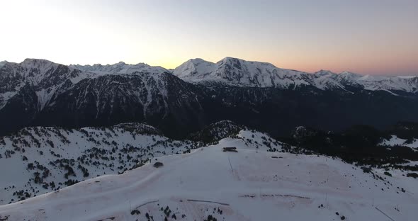 Chamrousse ski resort in the French Alps during sunrise with tracks below, Aerial pan left reveal sh