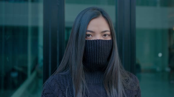 Beautiful Brunette Woman with Beautiful Long Hair Pulls a Black Sweater Over Her Face Looking