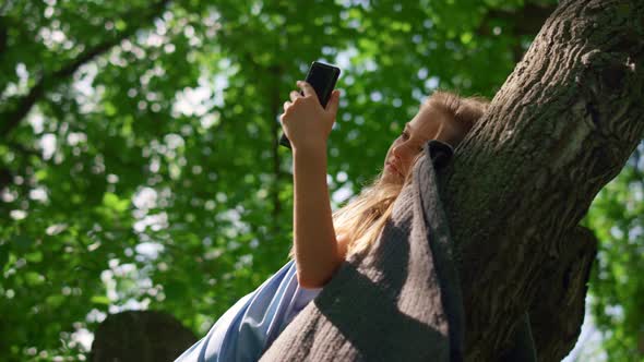 Girl Lying with Phone on Branch Close Up