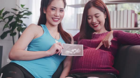 Pregnant Asian lesbian woman and her partner are happy to spend time together at home.