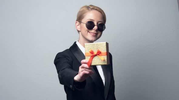 smiling businesswoman in a classic business suit and sunglasses gives a gift