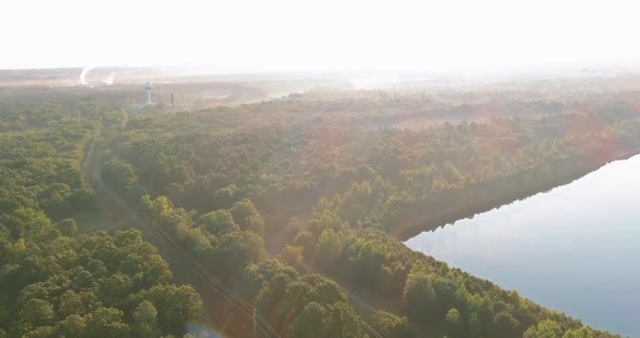 Beautiful Landscape with Green Forest Near a Foggy Over Lake in Panoramic Top View