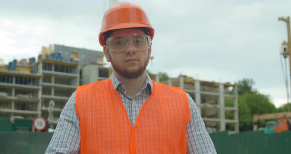 Portrait of an Architect or Builder in Hard Hat Standing in Front of Building Under Construction