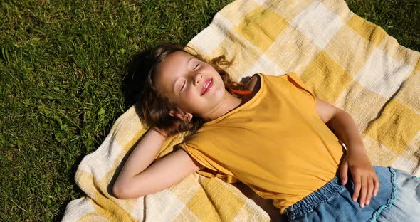 Child lying on the blanket, on the grass in the sun day, take sunbathes on backyard