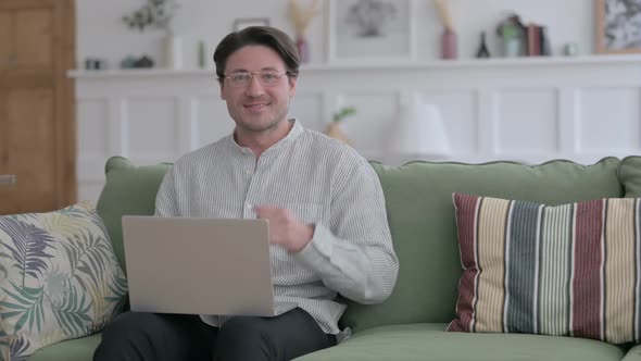 Man Showing Thumbs Up Sign While using Laptop on Sofa