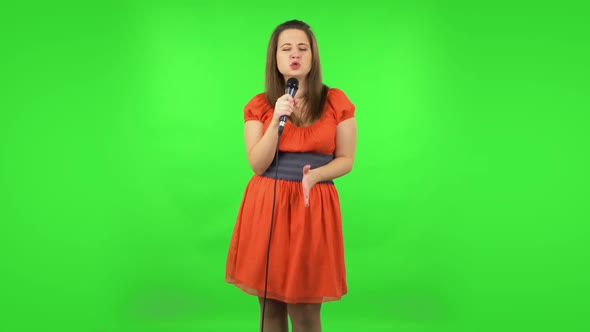 Cute Girl Is Singing Into a Microphone and Moving To the Beat of Music. Green Screen