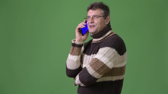 Mature Handsome Man Wearing Turtleneck Sweater Against Green Background