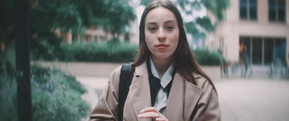 Woman walks under trees while looking around