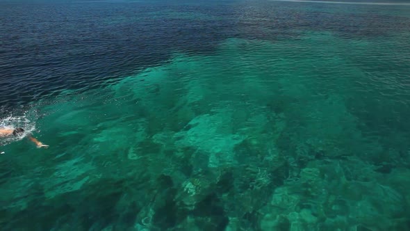 Man swimming in mediterranean close to sailing boat