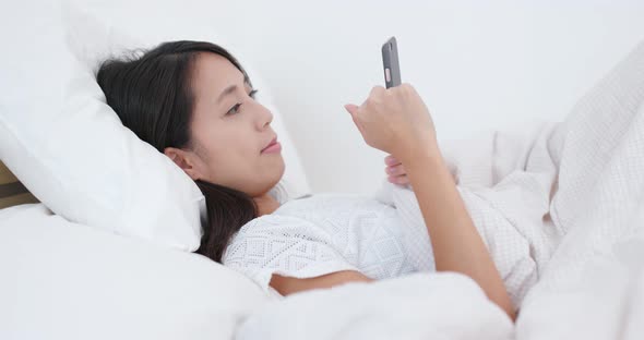 Woman use of cellphone and lying on bed