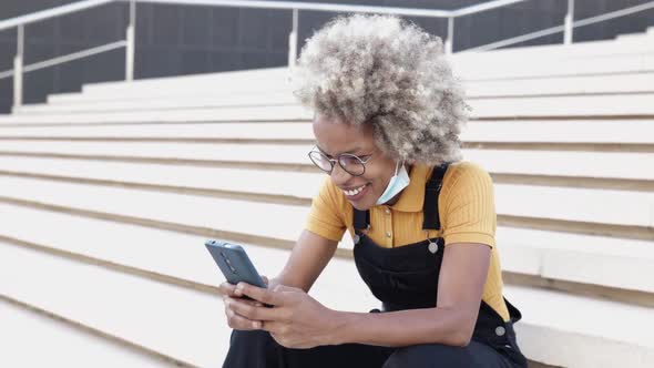 Portrait of Smiling Young Latino Woman Using Mobile Phone While Sitting Outdoors