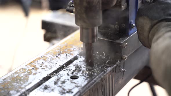 Drilling holes in iron profile with industrial machine.