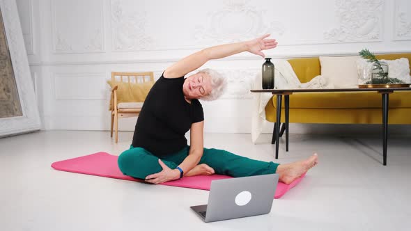 an Elderly Woman Does Yoga at Home