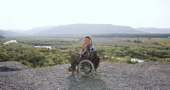 Disabled Man in Wheelchair After Desease or Accident which Praying on the Hill