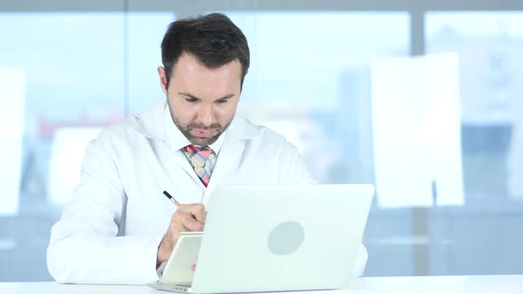 Doctor Writing Medical Reports of Patient Using Laptop