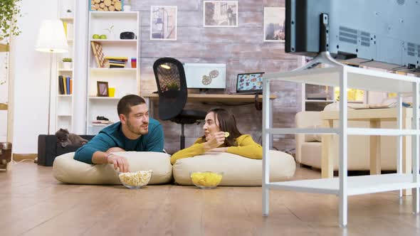 Couple Talking with Each Other Watching Tv Sitting on the Pillows for the Floor