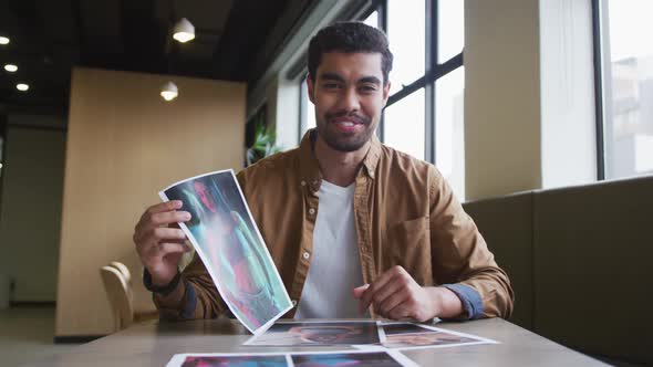 Mixed race businessman having a video chat going through paperwork modern office