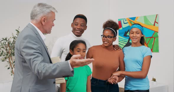 A Happy Family Stands in a Room While Inspecting an Apartment for Rent with a Real Estate Agent a