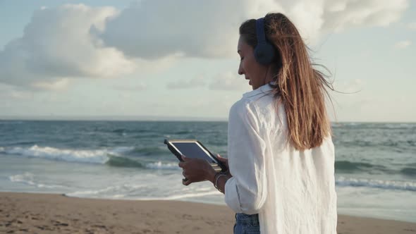 Woman with Tablet Walking by Ocean