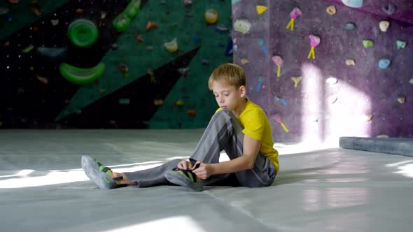 Teenage Climber Putting on Shoes in Climbing Gym