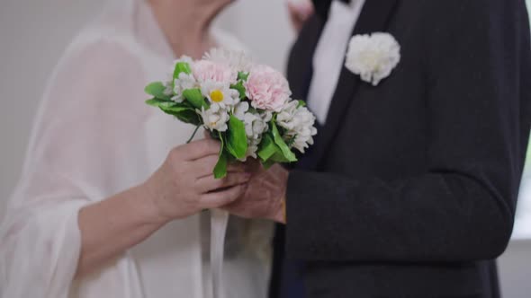 Closeup Bridal Bouquet in Senior Hand with Happy Groom and Bride Dancing in Slow Motion